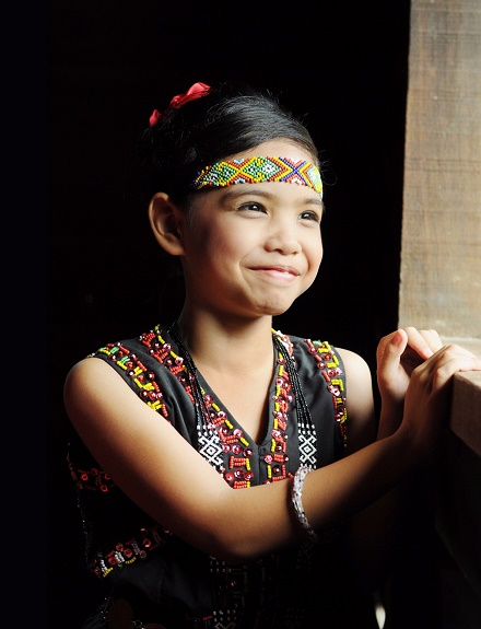 Kadazandusun young girl in traditional costume standing by the window