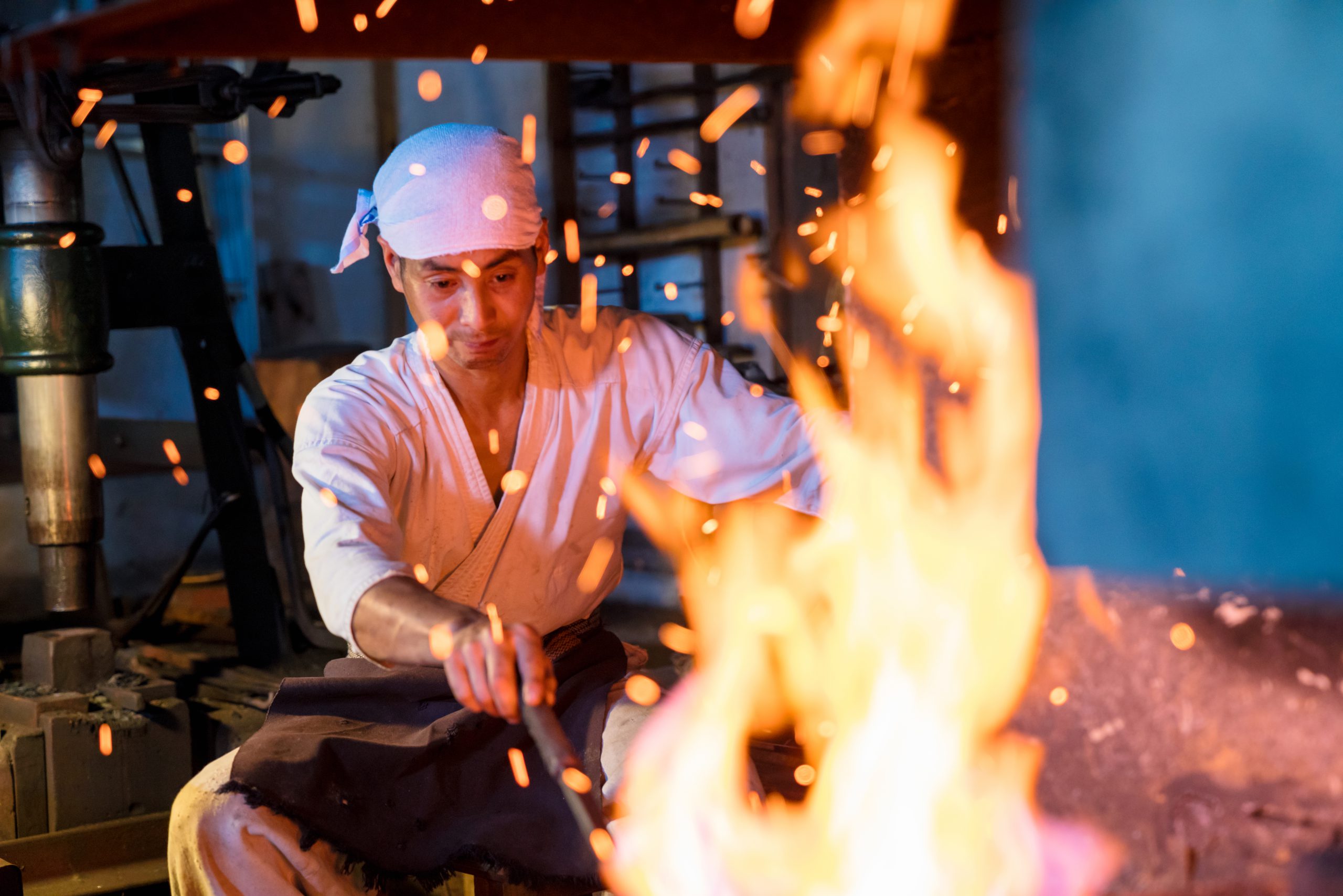 Japanese blacksmith stokes a fire preparing to forge a sword Japanese blacksmith stokes a fire preparing to forge a sword