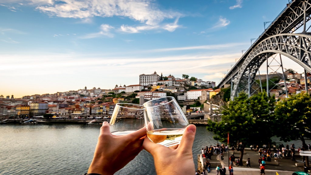 Couple toasting with the Douro river and Porto in background at sunset.